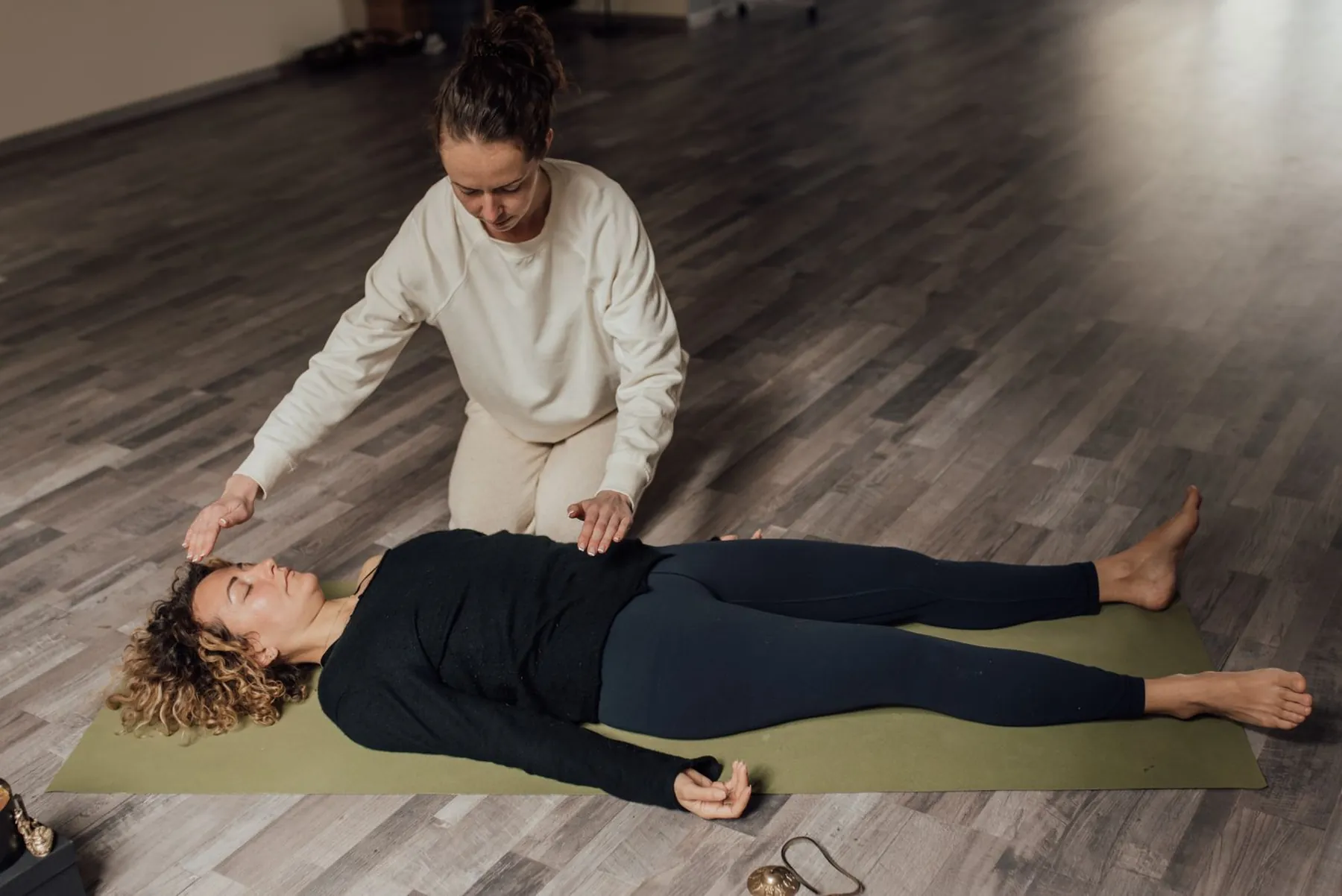 Vue de dessus d'une séance : une personne allongée et habillée, les mains du praticien au-dessus de sa tête et de son buste